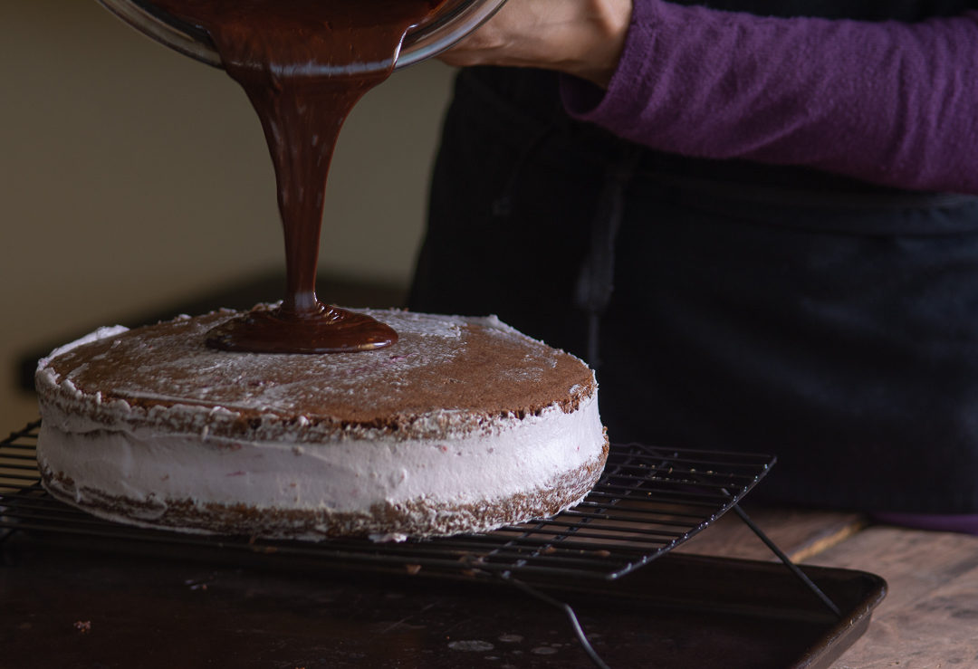 pouring chocolate ganache on cake